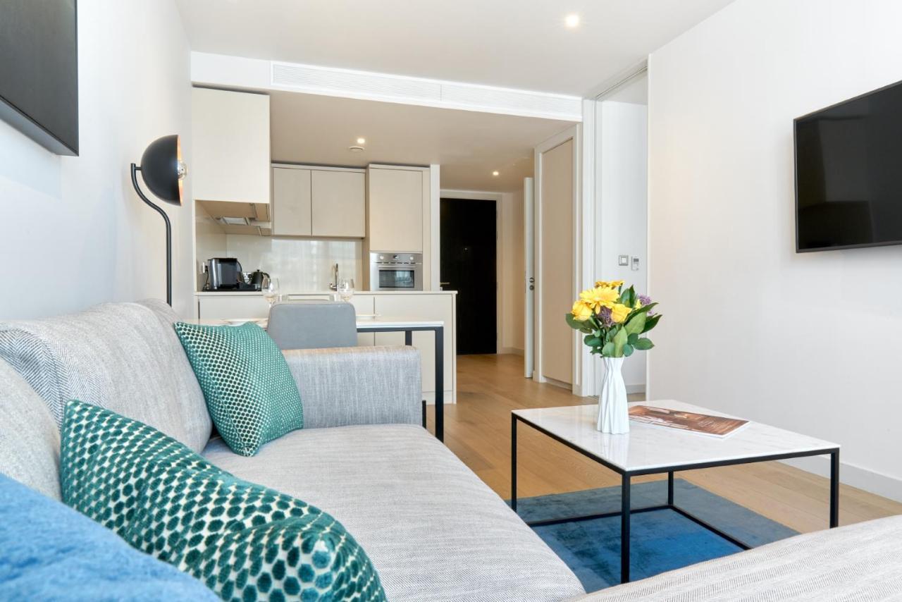 Citysuites Aparthotel Salford  Exterior photo The photo shows a modern and stylish living space. On the left, there is a light gray couch adorned with decorative pillows, including a blue one and a green patterned one. In front of the couch, there is a sleek coffee table with a vase of fresh flo