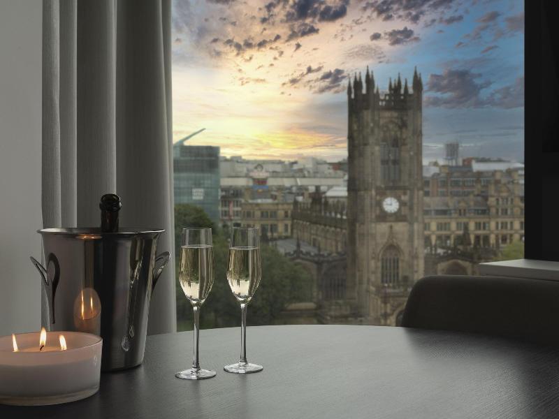 Citysuites Aparthotel Salford  Exterior photo The photo shows a cozy indoor setting with a table that features two champagne glasses and a bottle of champagne in an ice bucket. There is also a lit candle on the table, enhancing the intimate atmosphere. In the background, large windows reveal a c