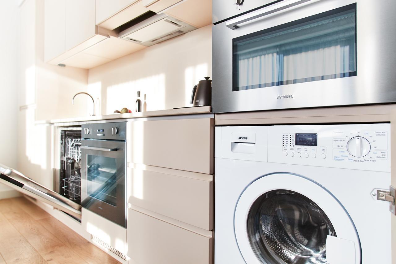 Citysuites Aparthotel Salford  Exterior photo The photo shows a modern kitchen area featuring several appliances. On the left side, there is a built-in dishwasher beneath a countertop. Next to it is an oven, also built into the cabinetry. To the right, there is a washing machine with a visible f