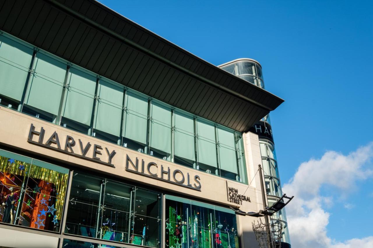 Citysuites Aparthotel Salford  Exterior photo The photo shows the exterior of a retail building featuring the name "Harvey Nichols" prominently displayed. The architecture includes large glass windows, and the design appears modern and sleek. The sky above is bright blue, suggesting a sunny day,