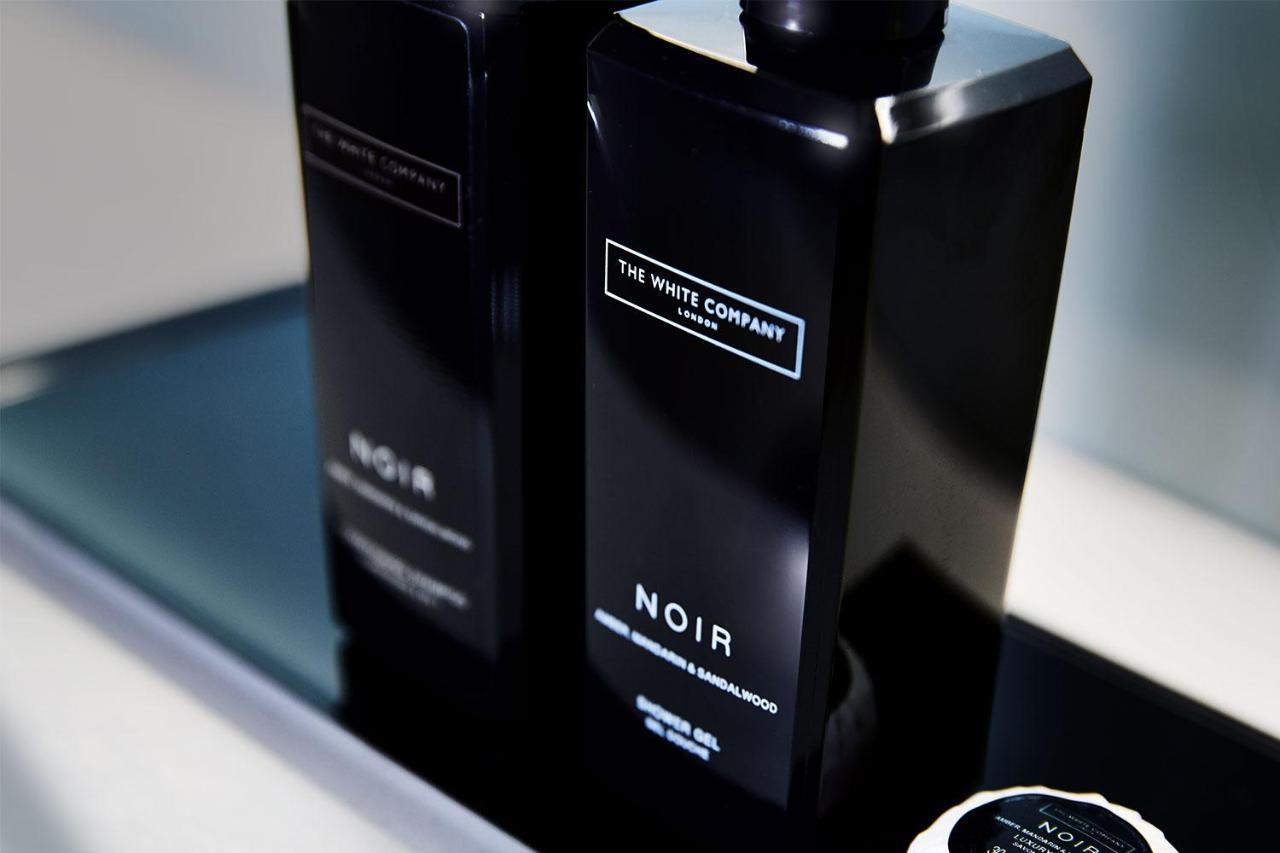 Citysuites Aparthotel Salford  Exterior photo The photo shows two sleek, black bottles labeled "NOIR" from "The White Company." They have a modern design with minimalistic branding. Next to the bottles, there appears to be a small circular item, possibly a lid or a coaster, also in black. The ar