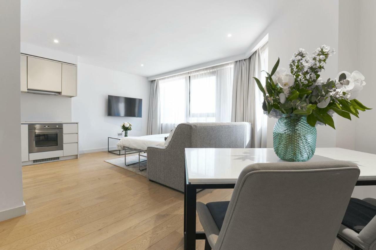 Citysuites Aparthotel Salford  Exterior photo The photo shows a modern and bright living space that combines a kitchen and living room area. 

- **Kitchen:** It features sleek, contemporary cabinetry, an oven, and a stove. 
- **Living Room:** There is a white sofa arranged for relaxation, and a 