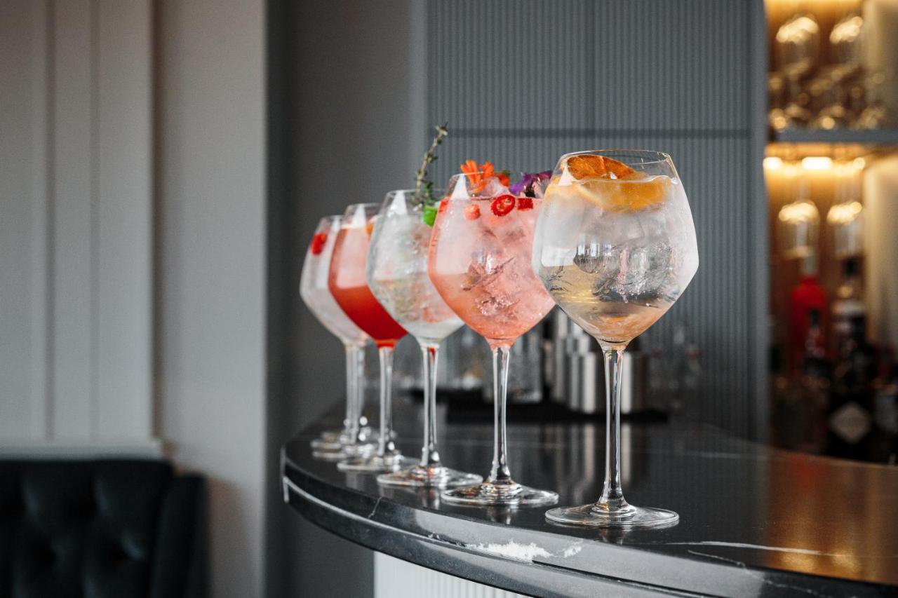 Citysuites Aparthotel Salford  Exterior photo The photo shows a selection of five elegant cocktails arranged neatly on a bar counter. Each cocktail is served in a large, round glass and features different colors and garnishes. 

- The first cocktail on the left appears to have a red hue with gar